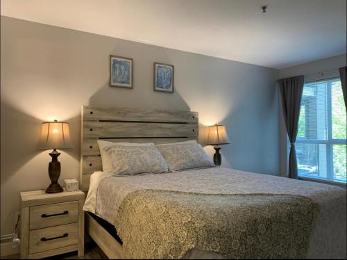 a bedroom with a bed and two lamps and a window at Waterscapes Osprey 2 Kelowna in Kelowna