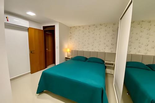 a bedroom with a blue bed and a brown door at Apto 3 quartos com piscina e pertinho da praia. in João Pessoa