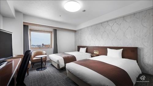 a hotel room with two beds and a television at Daiwa Roynet Hotel Hachinohe in Hachinohe