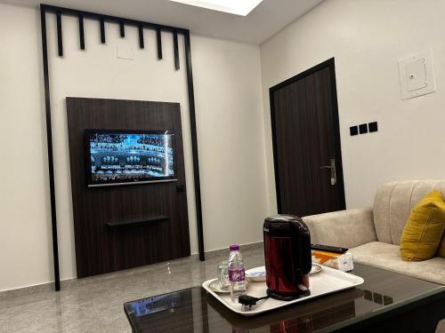 ein Wohnzimmer mit einem Sofa, einem Tisch und einem TV in der Unterkunft اجنحه ايلاف الفندقية in Abha