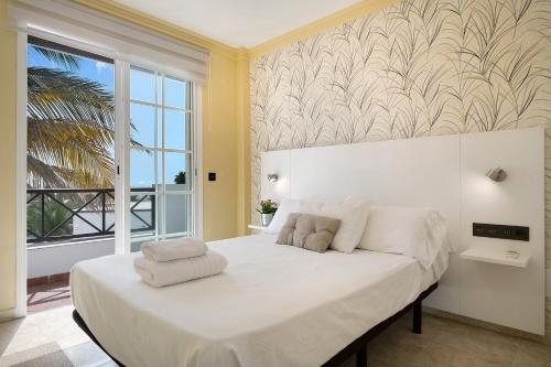 a bedroom with a large white bed with a large window at La Marina in Puerto del Carmen