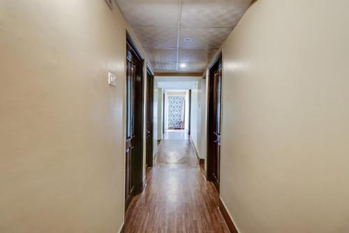 un pasillo vacío con un largo suelo de madera y paredes blancas en OYO Flagship M H Grand en Nalmatha