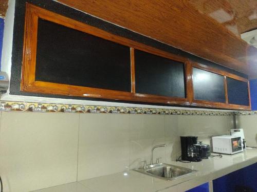a kitchen with a sink and wooden cabinets at Cabinas Pacifico in Puntarenas