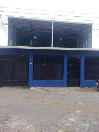 a blue garage with gates and a building at Cabinas Pacifico in Puntarenas