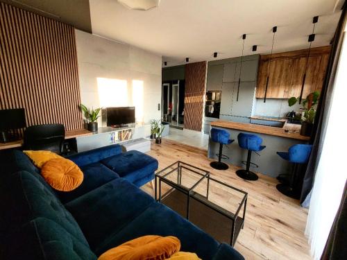 a living room with a blue couch and a kitchen at Modern apartment with spacious backyard by Matt in Warsaw