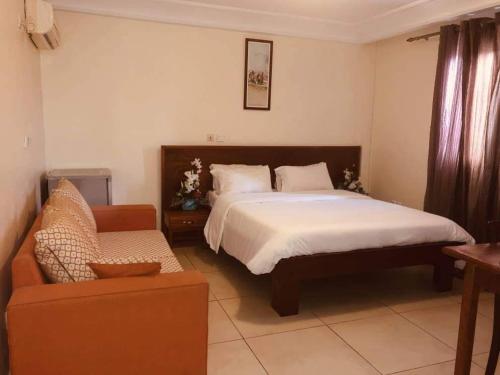 a bedroom with a large bed and a couch at Hannatel Rooms Liberté in Douala