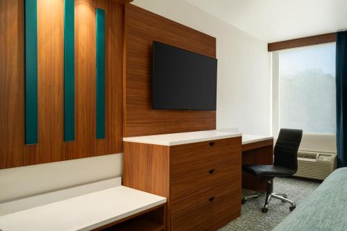 a room with a bed and a desk and a tv at Wingate by Wyndham Williamsburg in Williamsburg