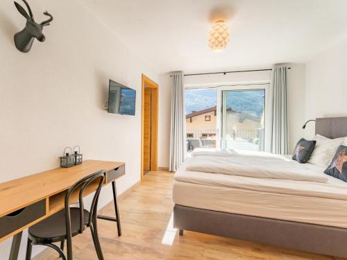 a bedroom with a bed and a desk and a window at Tauernlodge Berglust in Bramberg am Wildkogel