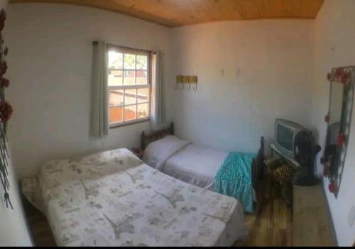 1 dormitorio con 2 camas y TV. en Pouso Casazul en Tiradentes