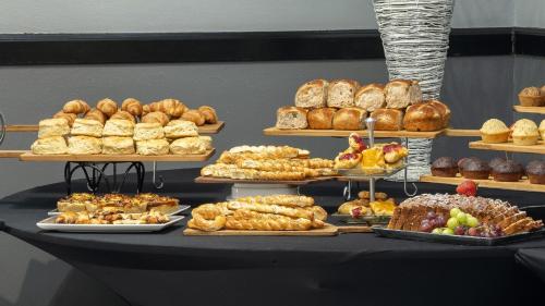 a table filled with different types of bread and pastries at Holiday Inn Johannesburg OR Tambo Airport Hotel by IHG in Kempton Park