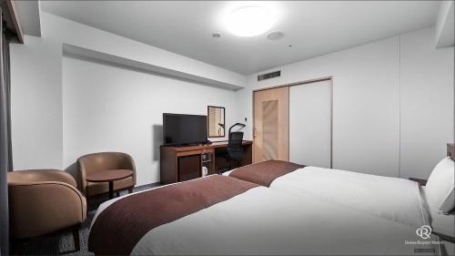 a bedroom with a bed and a desk and a television at Daiwa Roynet Hotel Hachinohe in Hachinohe