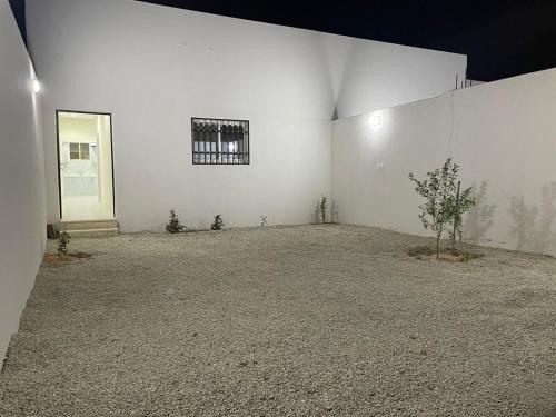 an empty room with a white wall and a tree at شقق خاصة مع حوش مدخل خاص in Sidīs