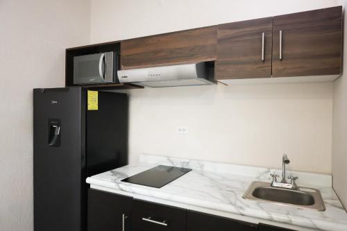 a kitchen with a sink and a black refrigerator at Aura Hotel boutique in Guadalajara