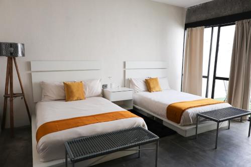 a hotel room with two beds and a window at Aura Hotel boutique in Guadalajara