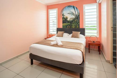 a bedroom with a large bed with an orange wall at Villa Lynko - 3 Chambres Climatisées - Jardin Tropical - Plages du Moule à 10 minutes in Le Moule