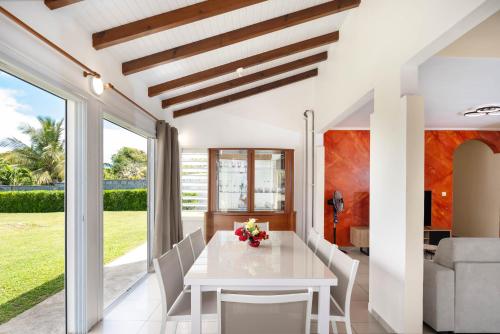a dining room with a white table and chairs at Villa Lynko - 3 Chambres Climatisées - Jardin Tropical - Plages du Moule à 10 minutes in Le Moule