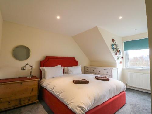 a bedroom with a red bed and a window at Oak Cottage in Torcastle