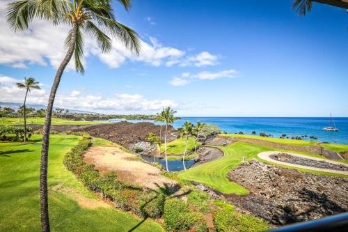 a view of a golf course with palm trees and the ocean at Mauna Lani Point in Waikoloa