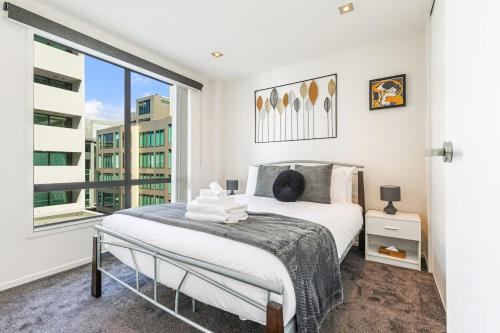 ein Schlafzimmer mit einem Bett und einem großen Fenster in der Unterkunft Serene 2Bed Gem with Free Parking in Auckland