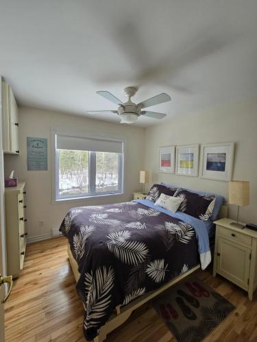 a bedroom with a bed and a ceiling fan at CITQ 303469.CHALET OASIS DE PAIX. BORD DE L’EAU.4 SAISONS.À LOUER in Chertsey