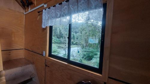 a window in a bathroom with a view of a forest at Cabañas & Habitaciones Del Alto in Hornopiren