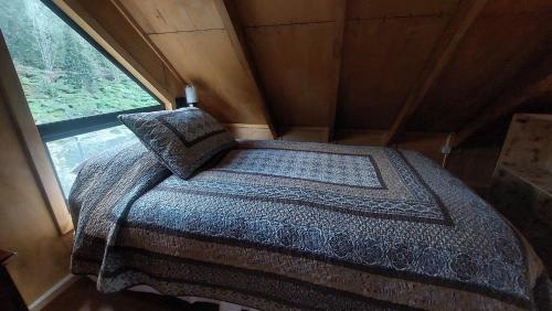 a bed in a small room with a window at Cabañas & Habitaciones Del Alto in Hornopiren
