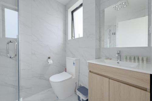 a white bathroom with a toilet and a sink at Modern 3-bds townhouse in South Auckland in Auckland