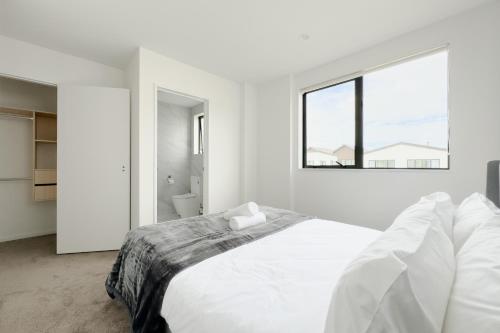 a white bedroom with a large bed and a window at Modern 3-bds townhouse in South Auckland in Auckland