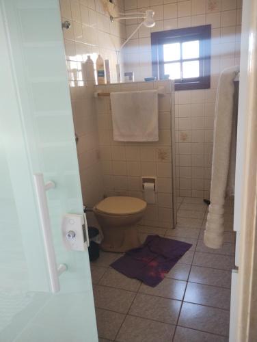 een badkamer met een toilet en een douche met handdoeken bij Perequê Mirim, Caraguatatuba in Caraguatatuba