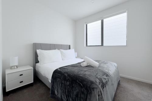a white bedroom with a bed and a window at Modern 3-bds townhouse in South Auckland in Auckland