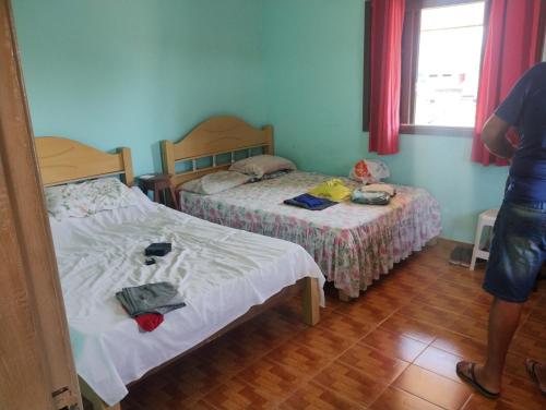 een slaapkamer met 2 bedden en een persoon in een kamer bij Perequê Mirim, Caraguatatuba in Caraguatatuba