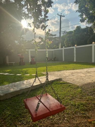 a swing in a yard with the sun shining at Villa Familiar con Piscina Privada y Rio in Bonao