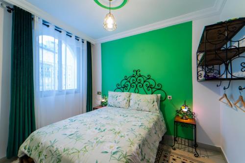 a green bedroom with a bed and a green wall at Dar Jinane in Chefchaouene