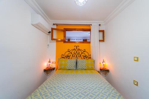 a bedroom with a bed with a yellow headboard and two lamps at Dar Jinane in Chefchaouene