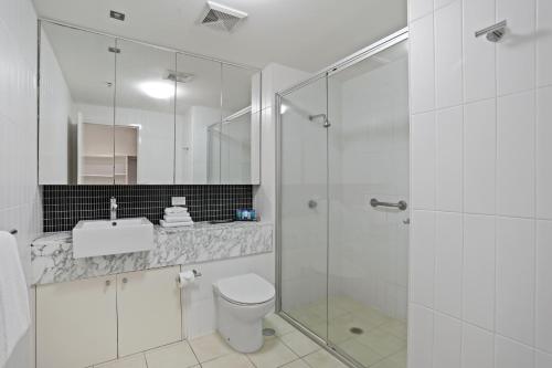 a bathroom with a shower and a toilet and a sink at Tweed Ultima Apartments in Tweed Heads