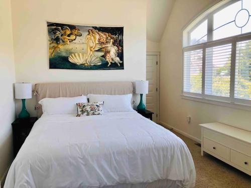 a bedroom with a white bed with a painting on the wall at Seagrass Cottage at Beverly Beach in Newport
