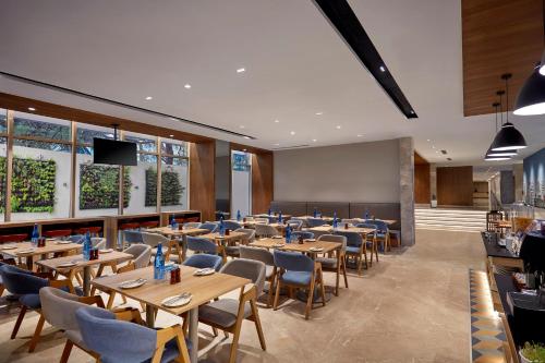 a dining room with wooden tables and chairs at Holiday Inn Express Bengaluru Bommasandra by IHG in Bengaluru
