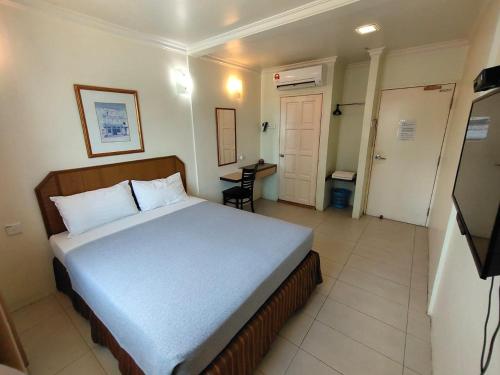 a bedroom with a bed and a table and a door at TRAVELLERS LODGE in Malacca