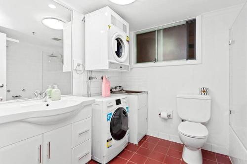 La salle de bains blanche est pourvue d'un lave-linge et d'un sèche-linge. dans l'établissement Inner City Retreat 1BD Pyrmont - 302, à Sydney