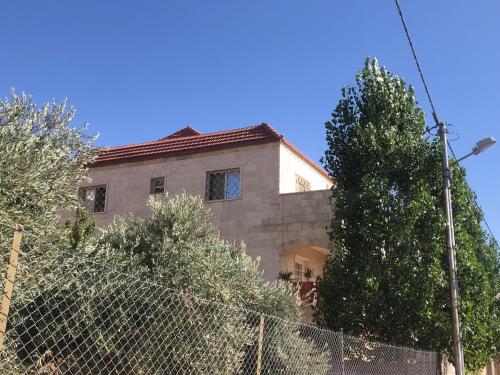 a house behind a fence with a tree at عجلون Ajloun in Ajloun