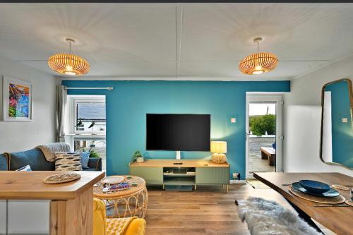 a living room with a blue wall and a tv at Nook Cottage Seaside Charm & Countryside Calm in Newquay