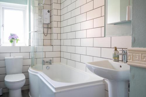 a bathroom with a tub and a sink and a toilet at Mallard house in Kent