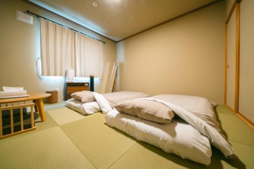 two beds in a room with a table and a window at TESHIKAGA HOSTEL MISATO in Teshikaga