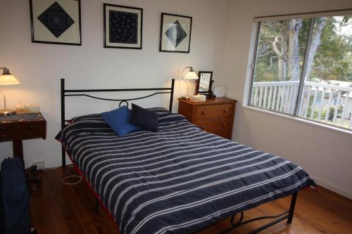 ein Schlafzimmer mit einem Bett mit blauen Kissen und einem Fenster in der Unterkunft Melaleuca in Manyana