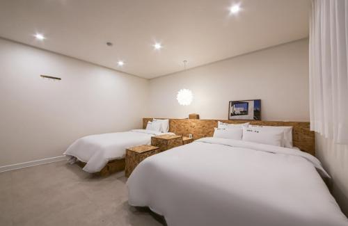 two beds in a room with white walls at The First Boutique Hotel in Gwangju