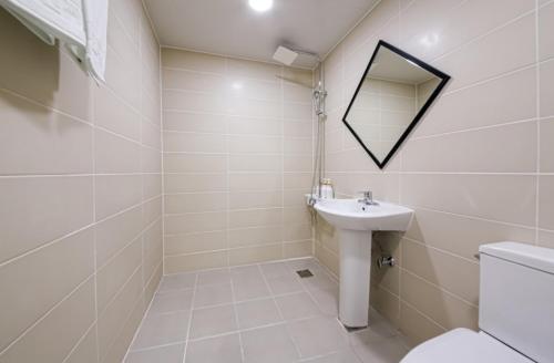 a bathroom with a sink and a toilet and a mirror at The First Boutique Hotel in Gwangju