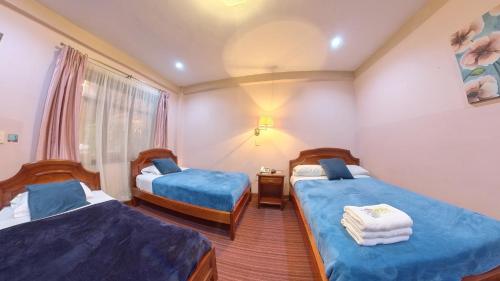 um quarto de hotel com duas camas e uma janela em Hostal Pichincha em Cuenca