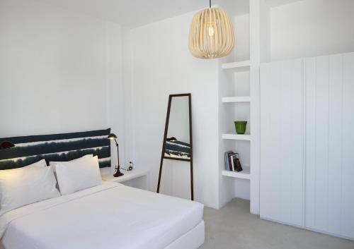 a white bedroom with a bed and a mirror at Bellonias Villas in Kamari