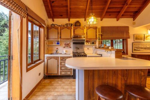 uma cozinha com armários de madeira e uma ilha com bancos de bar em Cabaña duplex el Sosiego. em El Tigre