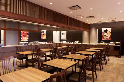 um restaurante com mesas de madeira e um bar em Kumamoto Washington Hotel Plaza em Kumamoto